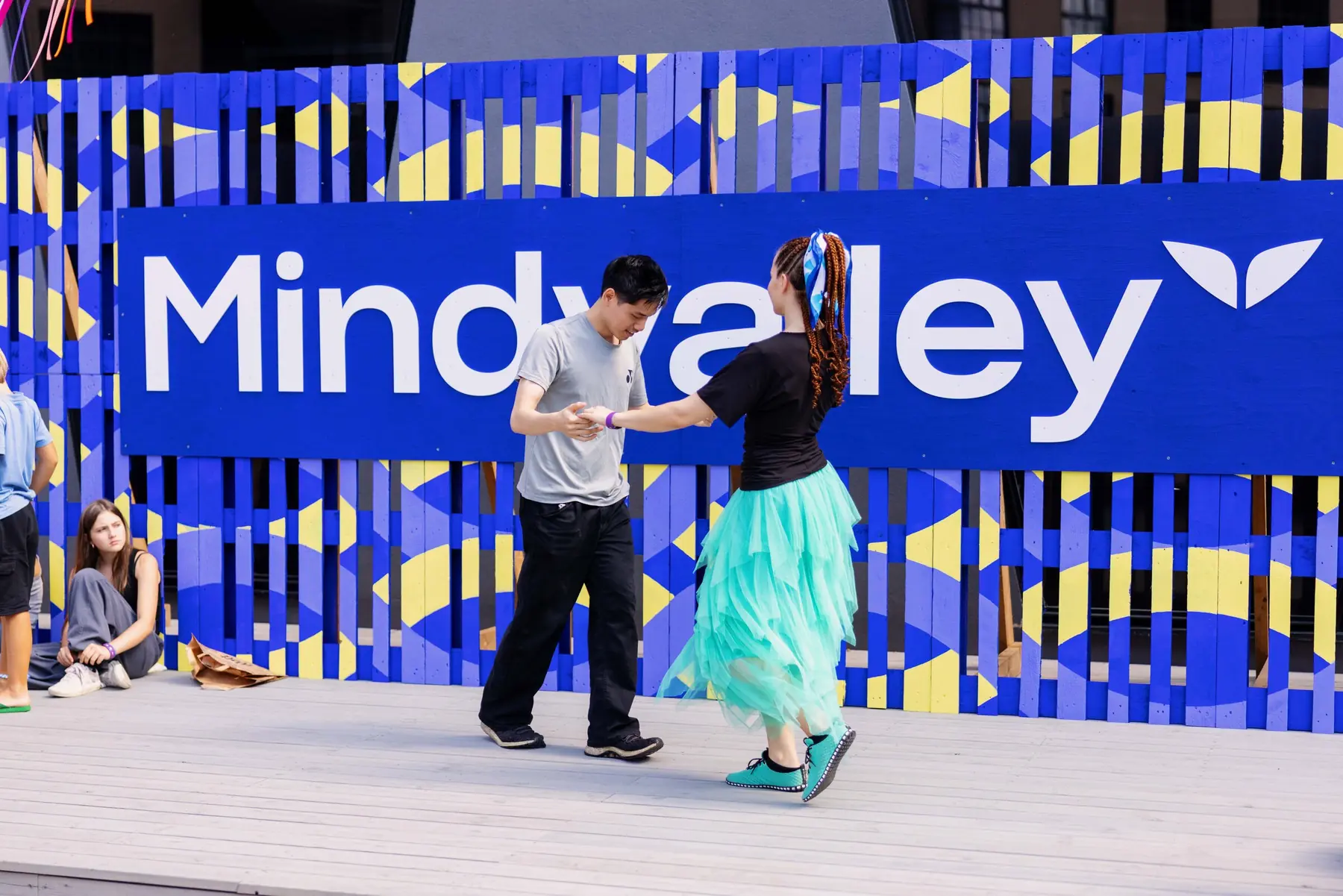 Attendees dancing in front of the Mindvalley sign wall