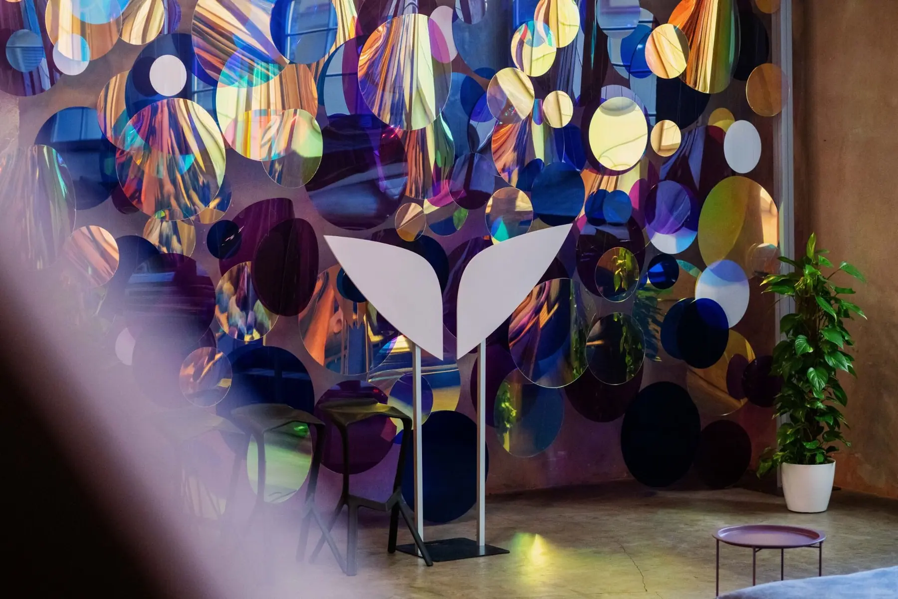 Mindvalley wings sculpture in front of an iridescent disc installation