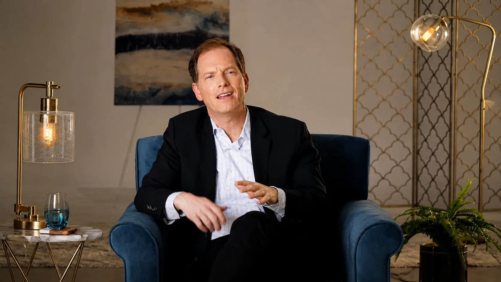 Speaker in an armchair on a warm, gallery-style set